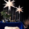 A festive table setting with Christmas decorations, including star lanterns, a Christmas tree branch, candles, and champagne. Produktbild-Vorschau