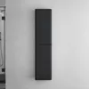 A tall, slender, black cabinet mounted on a textured white wall, with a sliver of a glass shower enclosure visible on the left. Anteprima dell’immagine prodotto