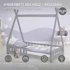 A light grey wooden cot with a tipi-like frame, set up in a child's bedroom with purple walls and decorative elements. Náhľad obrázku produktu