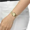 A woman's arm wearing a gold watch against a white background. Produktbild-Vorschau