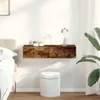 A floating shelf with two drawers is mounted on a white wall above a white stool, next to a bed and a large plant. Náhľad obrázku produktu