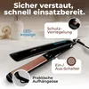 A black and rose gold hair straightener is shown on a light-colored countertop, with bathroom accessories in the background. Náhľad obrázku produktu
