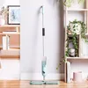 A spray mop is standing upright against a white wall, next to a wooden shelf unit with plants and books. Náhled obrázku produktu