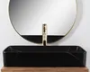 A black rectangular sink with a gold faucet in front of a round mirror. Produktbild-Vorschau