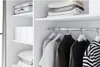 A clean and organized closet interior with clothing hanging on a rod and folded items on shelves. Produktbild-Vorschau