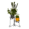 A black metal plant stand with three tiers holding three potted plants. Náhľad obrázku produktu