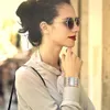 A woman wearing sunglasses and a watch, looking to the side. Produktbild-Vorschau