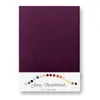 A flat lay image of a folded aubergine colored jersey fitted sheet on a white background. Below the sheet is a white label with a rainbow of small colored circles and text. Produktbild-Vorschau