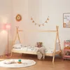 A child's bedroom with a teepee-style bed, a pink floor lamp, and decorative elements.