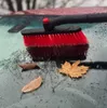 A red and black car brush is shown on a wet car windshield with fallen leaves. Anteprima dell’immagine prodotto