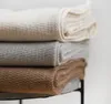 A stack of three folded blankets in different neutral colors. Produktbild-Vorschau