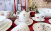 A Christmas-themed table setting with a tea set, candles, and cookies. Produktbild-Vorschau