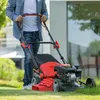 A person is mowing a lawn with a red and black lawnmower. Produktbild-Vorschau