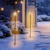 Two spiral Christmas trees with gold LED lights and star toppers are displayed in a snowy outdoor setting next to a white door. Voir les images du produit