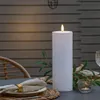 An outdoor table setting with a large LED candle as a centerpiece. Produktbild-Vorschau