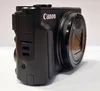 A close-up side view of a black Canon digital camera. Podgląd zdjęcia produktu