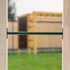 A green metal bar is mounted between two wooden posts, with a blurred playground structure in the background. Anteprima dell’immagine prodotto