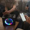 People are gathered around a table, holding microphones and interacting with a karaoke machine and a smartphone. Produktbild-Vorschau