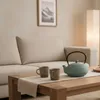 A living room scene with a sofa, coffee table, and a floor lamp. Náhled obrázku produktu