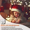 A young girl in a Santa hat writes a letter by the warm glow of Christmas lights. Náhled obrázku produktu