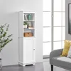 A white tall cabinet with shelves and a door, placed against a wall next to a window and a sofa. Produktbild-Vorschau