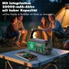 People camping around a campfire at night, with a solar radio on a table charging a phone. Produktbild-Vorschau