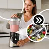 A woman is using a blender to make a smoothie in a kitchen. Produktbild-Vorschau