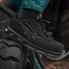 A person wearing jeans and a black safety shoe is stepping on a large tire. Voir les images du produit
