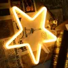 A neon star light is placed on a surface with decorative paper and books. Produktbild-Vorschau