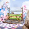 A miniature model of a green tram on a track, surrounded by cherry blossoms and a blue sky background. Produktbild-Vorschau