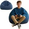 A young person is sitting on a large blue beanbag chair playing a video game. Voir les images du produit