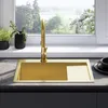 A modern kitchen sink with a gold faucet and sink basin, set against a window with a view of greenery. Náhľad obrázku produktu