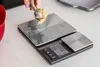 A person is using a kitchen scale to weigh cookie dough. Voir les images du produit