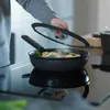 A person is cooking food in a frying pan on a stovetop. Podgląd zdjęcia produktu