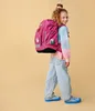 A young girl wearing a backpack and casual clothes, posing against a plain background. Náhled obrázku produktu
