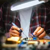 A person is soldering a circuit board under a bright lamp. Voir les images du produit