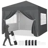 A dark gray pop-up canopy tent is shown with its sides open, revealing the interior. A silhouette of a person is standing to the left, holding a rolled-up bag. Several accessories are laid out in the foreground. Produktbild-Vorschau