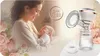 A mother holding her baby, with a breast pump and accessories on the side, and floral decorations. Produktbild-Vorschau