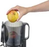 A hand is shown placing an apple into a juicer. Podgląd zdjęcia produktu