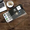 A smartphone with a protective screen protector lies on a wooden table next to a laptop and a plate of cookies. Produktbild-Vorschau