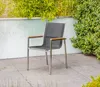 An outdoor chair sits on a patio with lush greenery in the background. Produktbild-Vorschau