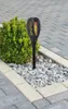 A solar-powered garden torch with a flame effect is placed in a garden bed with gravel and a small bush. Produktbild-Vorschau