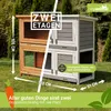 A two-story rabbit hutch is shown outdoors on a grassy lawn, with marketing text and dimensions overlaid. Produktbild-Vorschau