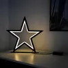 A star-shaped LED lamp sits on a white surface, casting a warm glow. Produktbild-Vorschau
