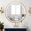 A bathroom vanity with a round, gold-framed mirror with integrated LED lighting, a gold faucet, and a soap dispenser. Produktbild-Vorschau