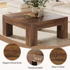A square coffee table with a dark wood grain finish is shown in a living room setting, with a sofa in the background. There are decorative elements on the table, and close-up insets highlight the wood grain, thickness of the material, and water resistance. Voir les images du produit