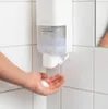 A hand is being washed with foam soap from a dispenser mounted on a tiled wall. Náhled obrázku produktu