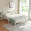 A white metal bed frame with a mattress and bedding is shown in a room with a large window. Voir les images du produit