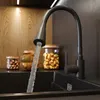 A kitchen sink with a black faucet running water into it, with jars of nuts and pistachios on the counter behind it. Produktbild-Vorschau