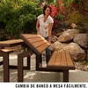 A woman is demonstrating how to convert a picnic bench into a table in an outdoor setting with rocks and plants. Podgląd zdjęcia produktu